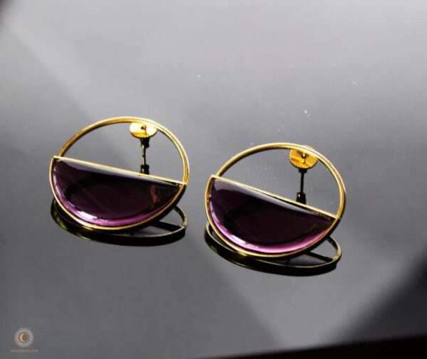 Purple glass earring on a black background