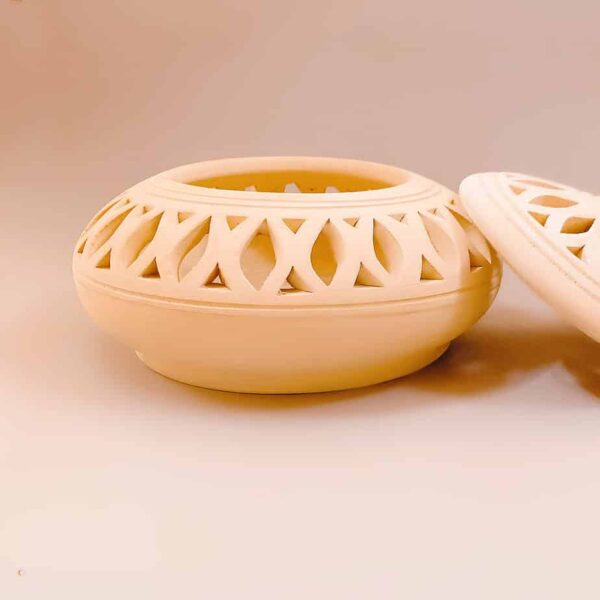 low and wide arabic pottery container with removable lid. Arabic pottery has carved cuts outs and made in Bahrain.
