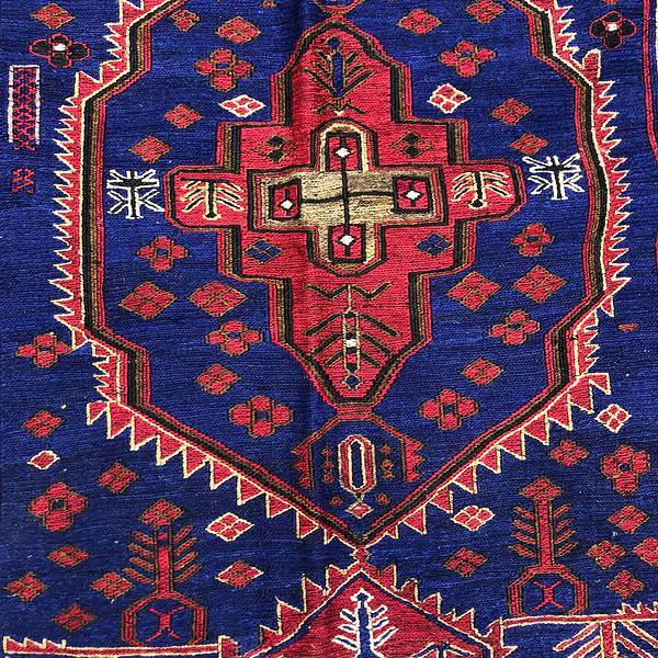 up close look at the pattern of a Balouchi Rug the kilim rug has a tight weave and the colours are blue red brown and cream.