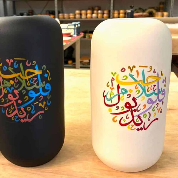 Large and long vase in cream and matte black both have Arabic Calligraphy painted on the vases.