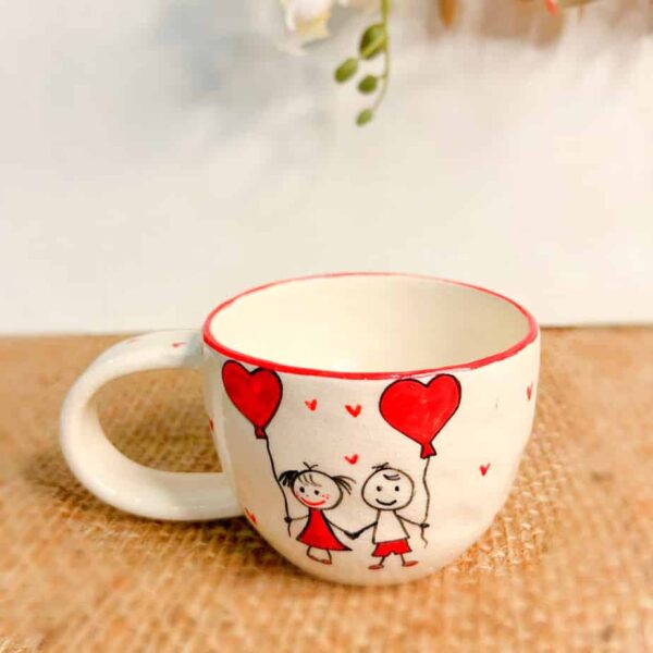 Handmade ceramic mug love and friendship, a boy and girl are holding hands and are holding red balloons in the shape of a love heart.