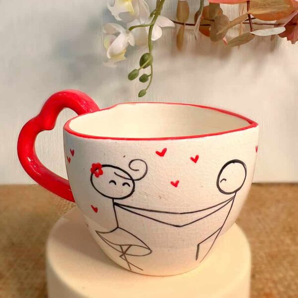 Handmade Ceramic Mug the mug has a handle in the shape of a love heart the front has a girl and boy holding hands.