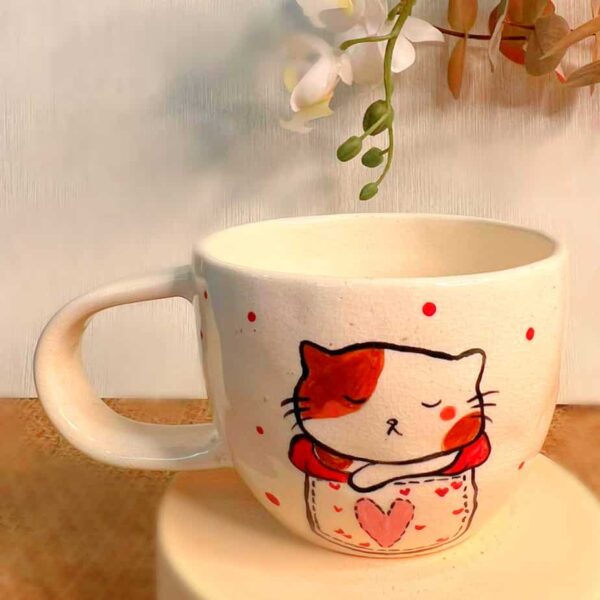 Handmade Ceramic Mug the mug has a picture of a cat on the front.