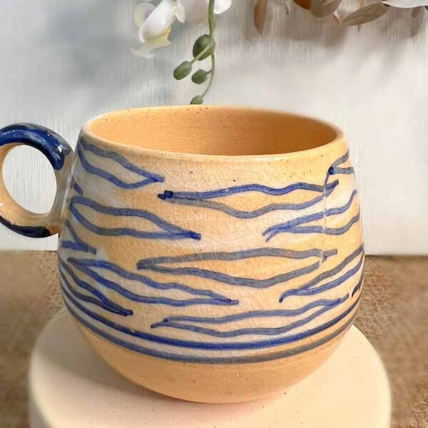 Handmade ceramic mugs with a blue wavy pattern.