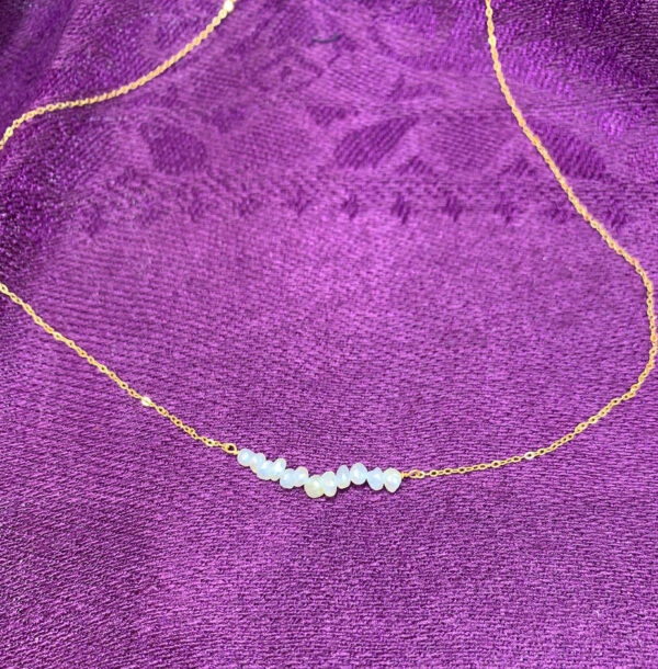 Gold chain and pearl necklace with a modern design.
