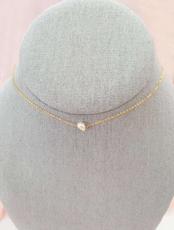 Pearl necklace with a delicate gold chain and a single pearl pendant, showcased on a grey jewelry stand. Perfect for elegant occasions and gift-giving.