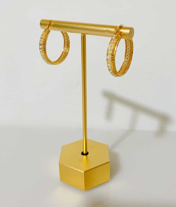Gold hoop earrings with embedded gemstones showcased on a stylish jewelry display stand. Perfect for retail stores, online shops, or personal collections to highlight jewelry pieces.