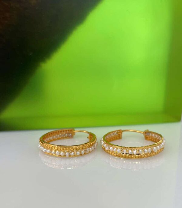 Gold hoop earrings adorned with sparkling pearls, perfect for stylish occasions and everyday wear. Crafted with high-quality materials, these earrings add a touch of sophistication to any outfit.