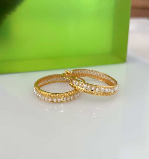 Elegant gold hoop earrings adorned with pearls and gemstones, perfect for special occasions or everyday wear.