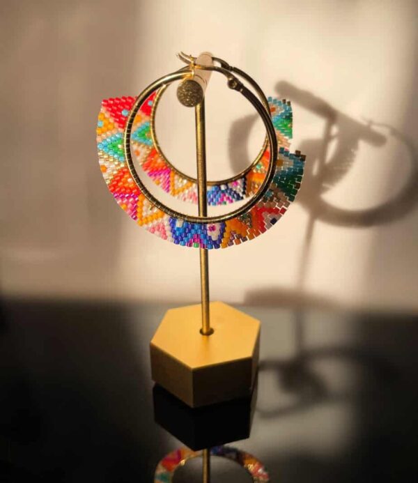 Colourful beaded hoop earrings showcased on a stand, highlighting traditional craftsmanship and vibrant design, perfect for bohemian or ethnic fashion styles.