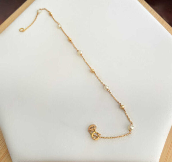 Elegant gold chain necklace with pearl accents, perfect for women’s fashion and accessories.