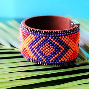 Cuff bracelet made with micro beads on suede leather, colorful aztec design.