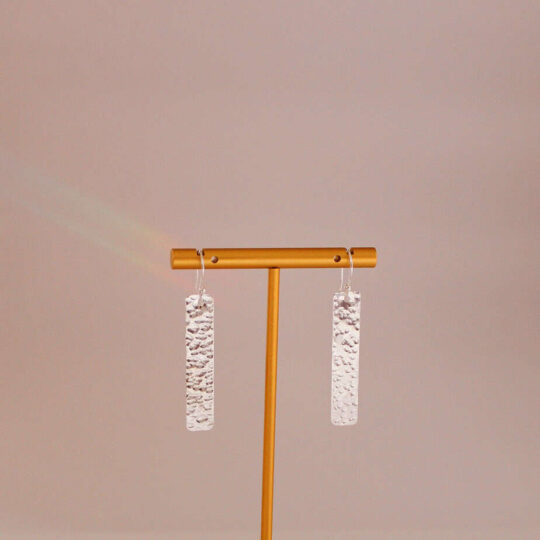 Elegant white textured dangle earrings displayed on a minimalist gold earring stand, perfect for fashion accessories and jewellery shopping at Souq2Door.