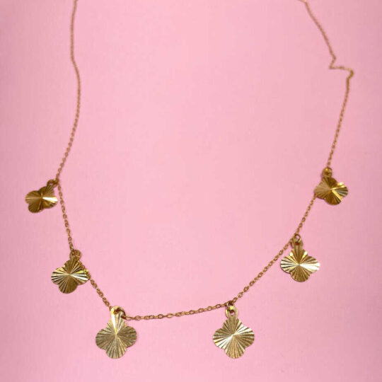 Gold necklace with leaf-shaped charms on pink background, stylish jewellery for women, trendy gold chain accessory, Dainty gold pendant necklace, gold leaf necklace for fashion jewelry relevance.