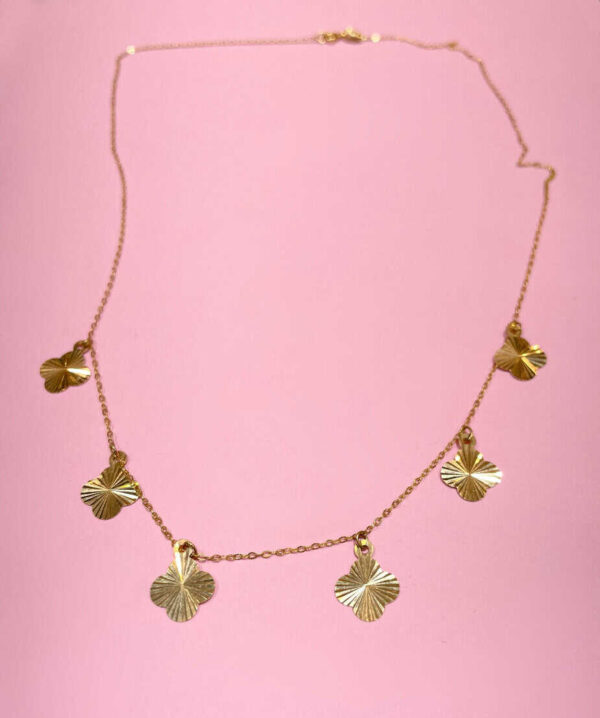 Gold necklace with leaf-shaped charms on pink background, stylish jewellery for women, trendy gold chain accessory, Dainty gold pendant necklace, gold leaf necklace for fashion jewelry relevance.