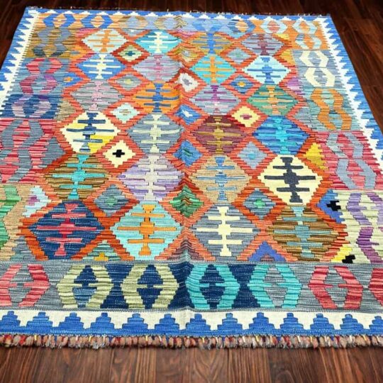 Vibrant geometric Turkish kilim rug with multicoloured patterns on dark wooden floor, traditional handmade home decor, ideal for living room or bedroom accents.