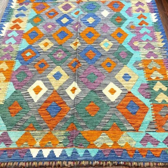 Vibrant colorful geometric patterned rug with diamond and heart motifs, perfect for adding ethnic and bohemian style to living spaces. Ideal for home decor, made from woven textile material.