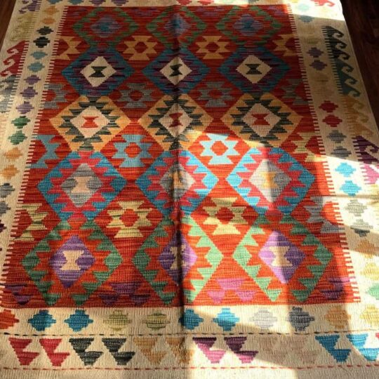 Vibrant geometric patterned traditional rug in warm colours, perfect for adding cultural charm and comfort to living rooms or bedrooms.