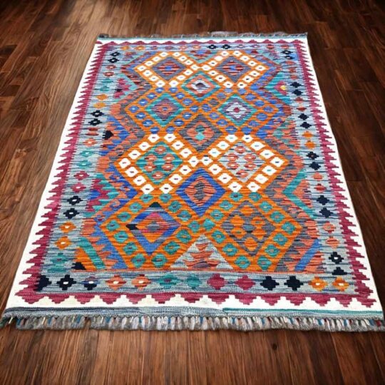 Vibrant geometric patterned area rug with traditional tribal design in orange, blue, teal, and white colours, ideal for home decor and adding cultural elegance to living spaces.