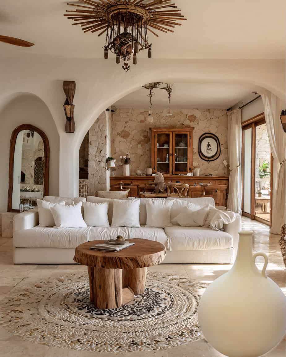 Large Cream Arabian Water Jug set in a Natural stone and wood interior of a cosy living room with cream sofa, rustic wooden coffee table, antique wall decor, large windows with curtains, and Mediterranean style design elements.
