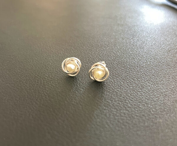 Elegant pearl stud earrings with silver swirl design, perfect for sophisticated fashion accessories. Suitable for all occasions, highlighting timeless jewellery style.