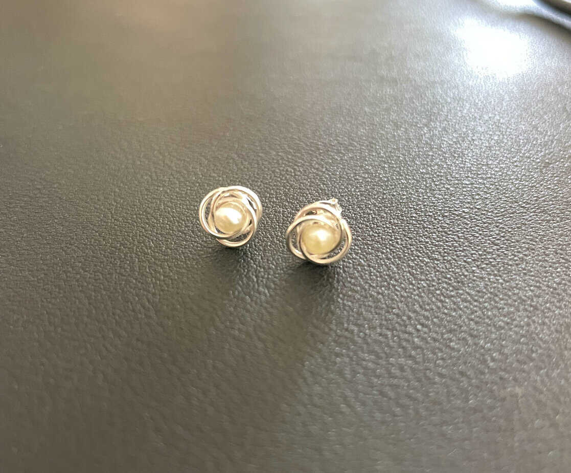 Elegant pearl stud earrings with silver swirl design, perfect for sophisticated fashion accessories. Suitable for all occasions, highlighting timeless jewellery style.