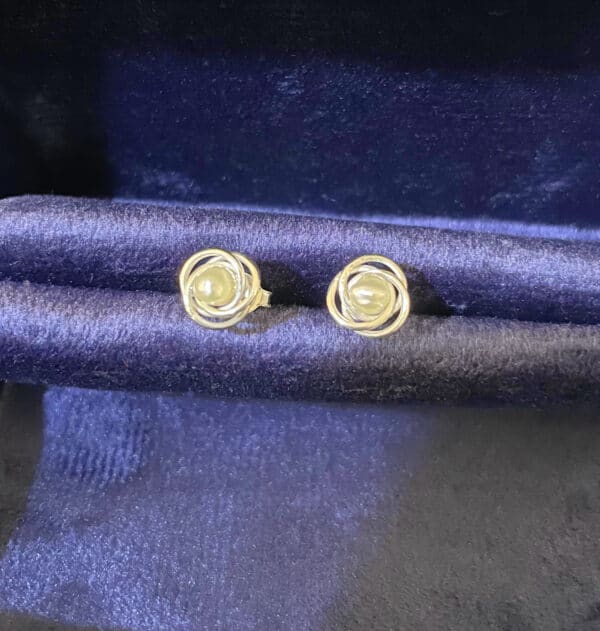 Elegant pearl and silver stud earrings displayed on a dark satin fabric, ideal for jewellery collections and fashion accessories. Perfect gift for special occasions and stylish outfits. The pearls are natural pearls from Bahrain Waters.