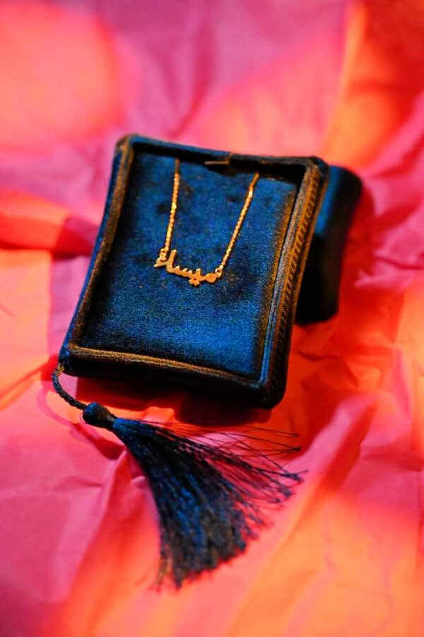 Gold name in Arabic Calligraphy necklace featuring Arabic script displayed on a luxurious blue velvet jewellery box, with a decorative tassel, perfect for celebrating special occasions.