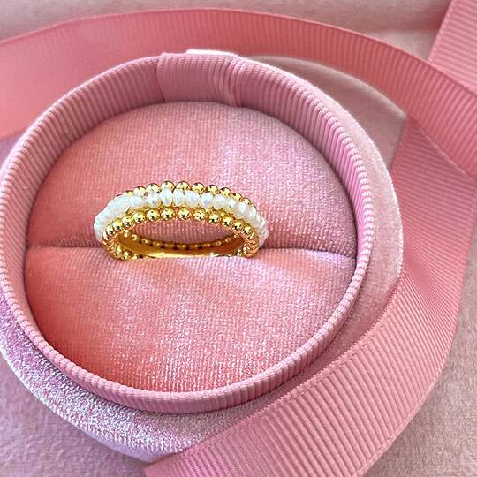 A beautiful gold ring adorned with lustrous pearls, displayed inside a plush pink velvet jewellery box with a satin ribbon, perfect for jewellery gifting or collection.