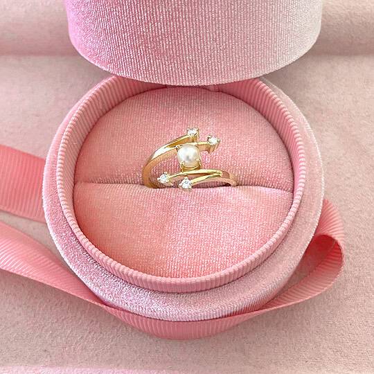 Delicate gold ring with pearl and small sparkling gemstones, presented in a soft pink velvet jewellery box, perfect for special occasions or as a heartfelt gift.