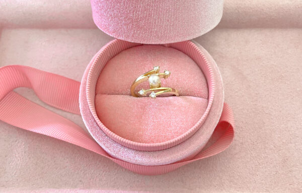 Delicate gold ring with pearl and small sparkling gemstones, presented in a soft pink velvet jewellery box, perfect for special occasions or as a heartfelt gift.