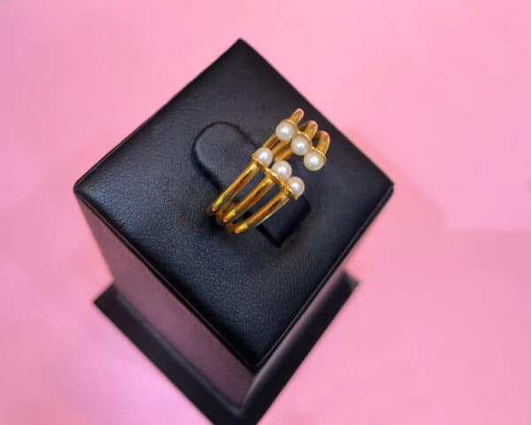 A luxurious gold ring adorned with natural Bahraini white pearls, displayed on a black ring box against a pink background. Perfect for elegant occasions and statement jewellery.