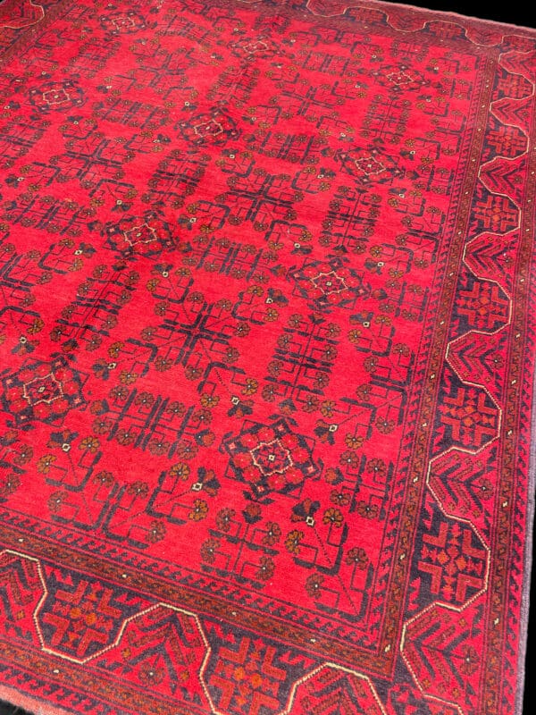 High-resolution image of a detailed red Persian rug showcasing intricate geometric patterns and floral motifs, perfect for adding a touch of elegance to home decor. The Rug is a handmade rug from Afghanistan made with natural dyes and created entirely by hand.