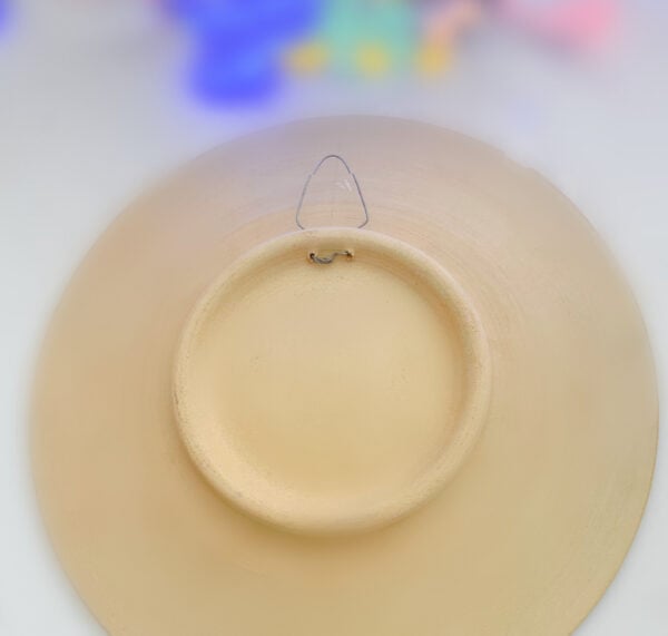 This photo shows the reverse side of an Arabian Art Piece it is a Clay Ceramic plate with a small hook, ideal for hanging on any wall or as a decorative piece. Crafted from Bahrain Clay, perfect for cultural decor with a unique flare.