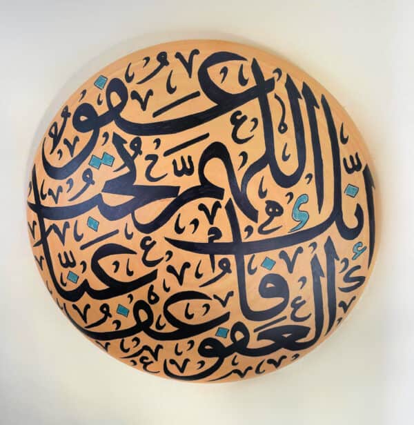 Beautiful Arabic calligraphy artwork featuring elegant black script with blue accents on a circular wooden plaque.