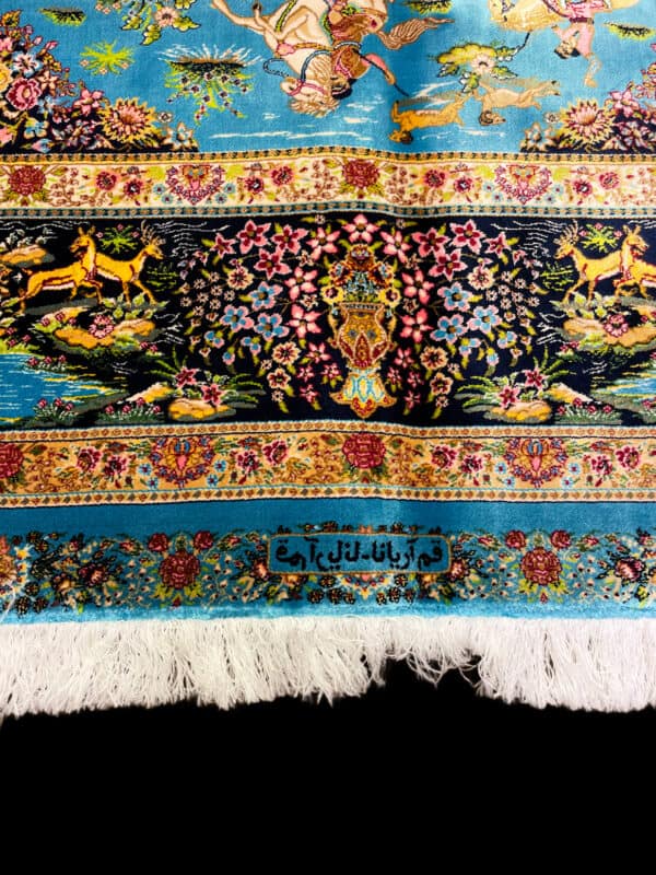 A vibrant Silk Persian rug featuring intricate floral patterns and elegant animal designs on a bright blue background. Handwoven with detailed craftsmanship, showcasing traditional Persian artistry.