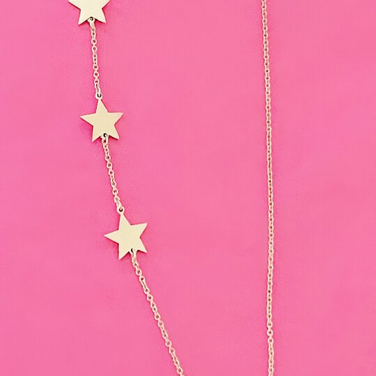 Elegant star pendant necklace with three gold stars on a delicate chain, displayed against a vibrant pink background. Perfect accessory for stylish and trendy outfits.