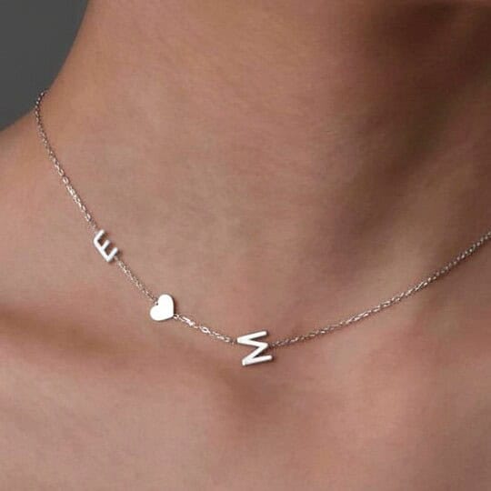 Necklace with silver letters spelling "E" and "M" and a small heart charm, perfect for personalized accessories.