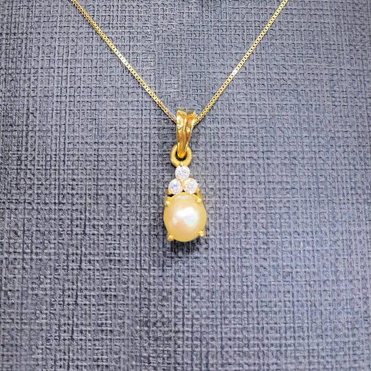 Pearl and diamond pendant necklace in gold, featuring a central pearl surrounded by sparkling diamonds, hanging on a delicate gold chain. Perfect for special occasions and elegant accessories.