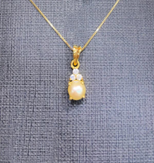 Pearl and diamond pendant necklace in gold, featuring a central pearl surrounded by sparkling diamonds, hanging on a delicate gold chain. Perfect for special occasions and elegant accessories.