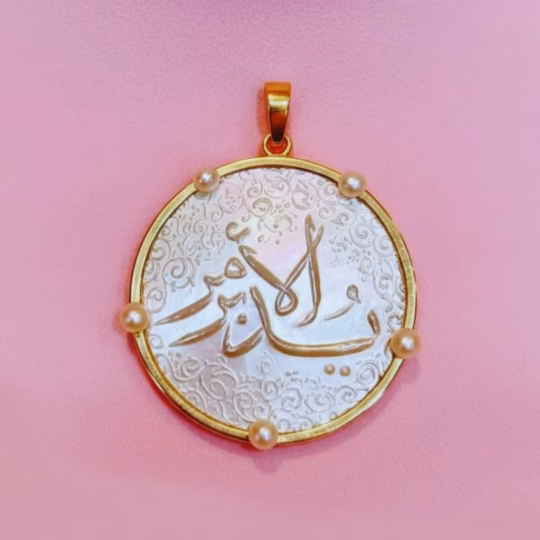 A stunning gold and mother of pearl unique pendant. The pendant has natural pearls from Bahrain on the outer casing. The inscription is engraved with a name in Arabic Calligraphy